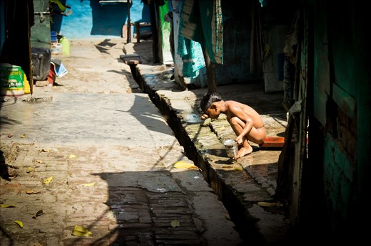 A boy takes a bath outside his slum home