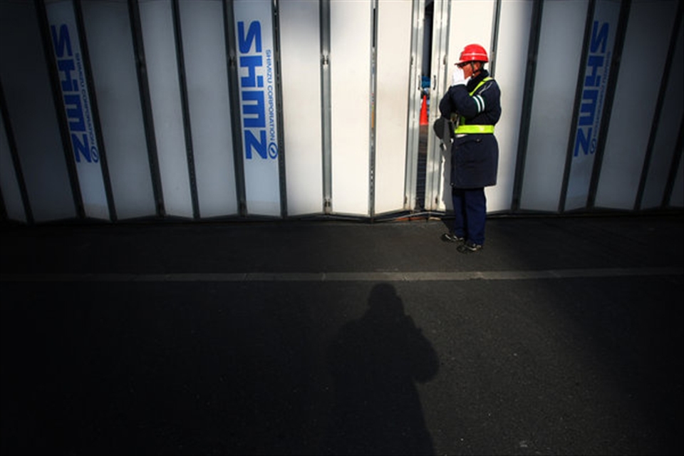 A worker blowing with cold hands, in one of the streets in the city of Tokyo.