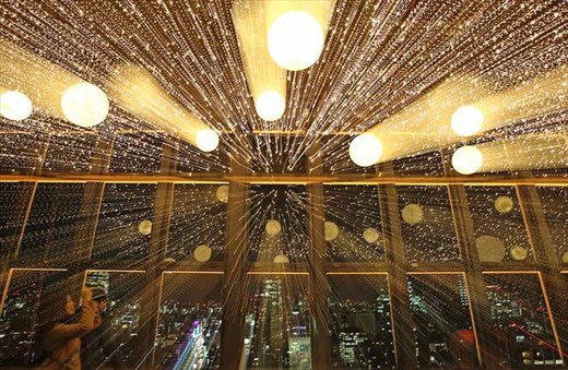 A female tourist photographing rows of lights on display at the Tokyo Tower. 