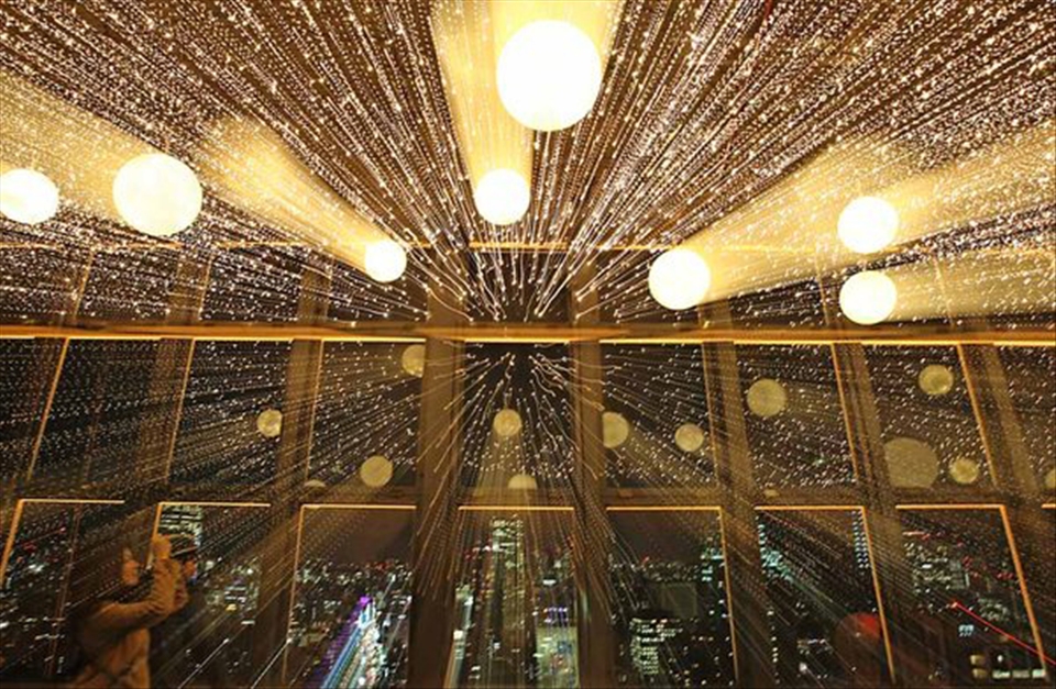 A female tourist photographing rows of lights on display at the Tokyo Tower. 