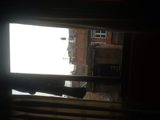 The tenement next door and track suit pants hanging to dry on curtain rod