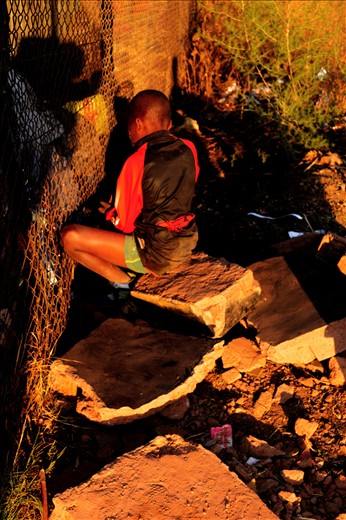 A boy who found a toy in the dump site and is now hiding it away from his friend