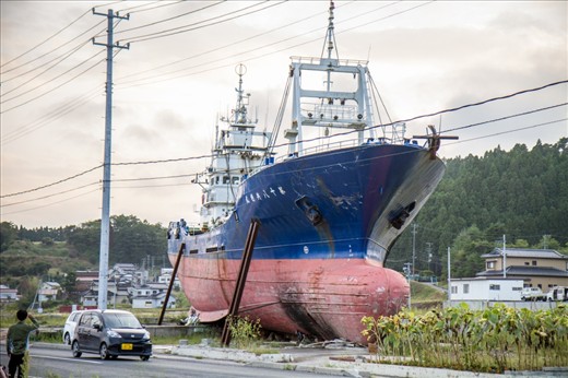 The March 2011 Pacific Coast Earthquake and Tsunami was truly devastating. I recently got to visit areas in the Miyagi province ruined by the disaster, like Kesennuma. When this ship loomed out of the dusk as we drove through the devastated city, I could do nothing but gasp and a cold feeling washed over me. Asking to stop the car, I got out and noticed the ship completely blocked off an entire side road, lying across it like an eerie blockade, surrounded by a makeshift shrine with flowers. I couldn’t grasp the sheer vastness of it but my Japanese colleague explained it had been one of many, many ships, some even bigger, that had been catapulted inland with the almighty tsunami. The rest were removed eventually, but this one remains as a memorial, a decision that has divided local residents: some feel it is a poignant reminder of all those that lost their lives, others feel it is too painful to see it everyday.