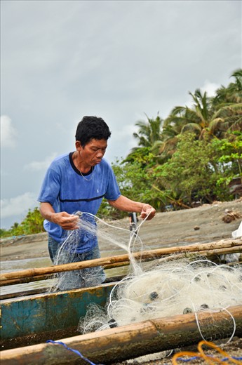 A fisherman fixing his nets getting ready to do what they do best. 