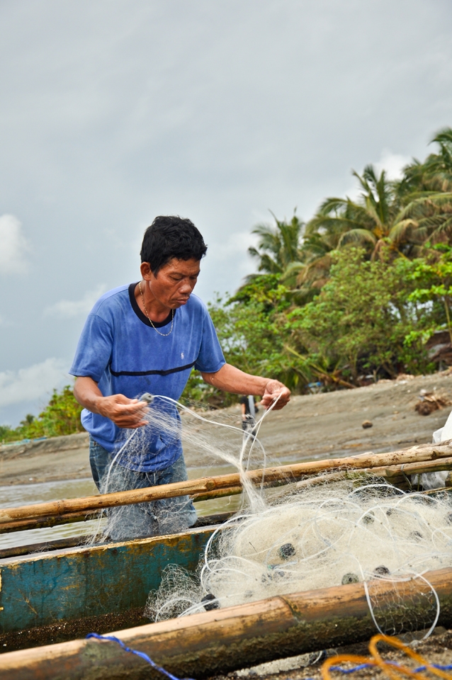 A fisherman fixing his nets getting ready to do what they do best. 