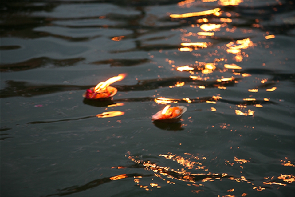 Tokens of candles and marigolds in banana leaf pots float down the Ganges.