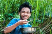 A boy smiling at me while having his lunch at the river.: by iamdikya, Views[707]