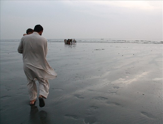 My house-keeper carrying his young son, walks towards the water. His name is Badshah & he requested that his face not be revealed. His father was an Afghan refugee who worked for my extended family. I met Badshah when he was a young boy. After his father's passing, he was raised by my god mother to whom he is ever loyal to this day. Badshah is content with very little. I once asked him if he wished he was richer. He said no. His struggle makes him more grateful for what he has. Not many people are as lucky, he said. It was heartening to see the genuine simplicity in the normal & routine movements of daily living & that people still preferred a simple life. 
When I first arrived in Karachi, Badshah had heard that my wish was to walk on Karachi's sandy beaches. These places hold fond memories as my family use to frequent them often when I was a child. To my pleasant surprise, with only a few days left to my departure, my wish came true when Badshah & his family took me to Seaview & Clifton beaches. I am forever indebted to his generosity & service. 