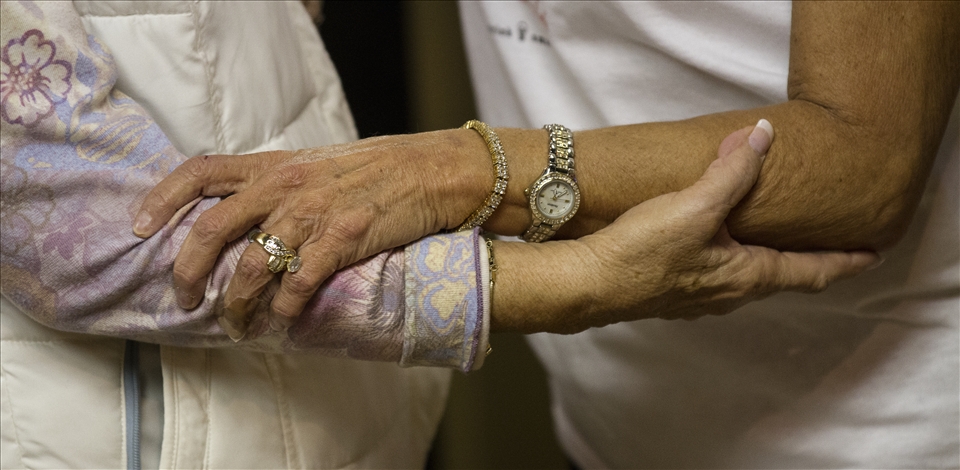 Two friends clasp arms as they greet one another at lunch.