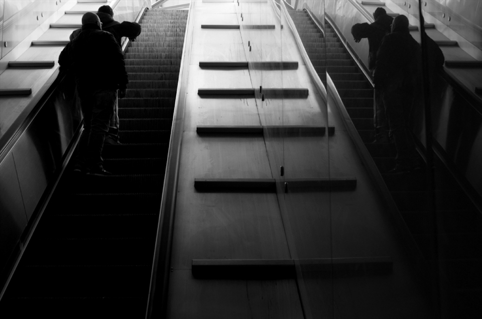 Naples City Metro entrance. Two men going up, together with their reflections. During the day we can see a lot of men in middle age just walking around, sitting, drinking coffee.