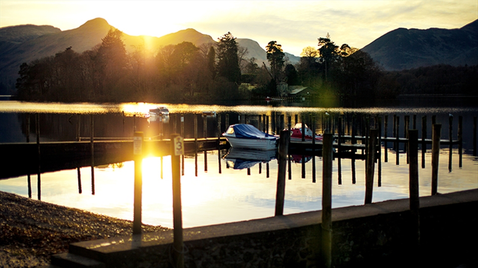 The smooth surface of the lake reflected the lights of the sunset.