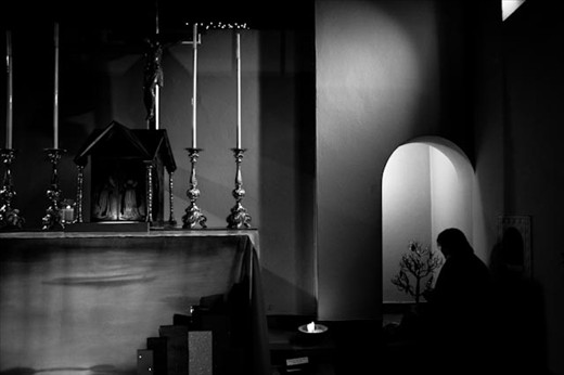 A silent figure engrossed in her rituals of worship in a quiet chapel