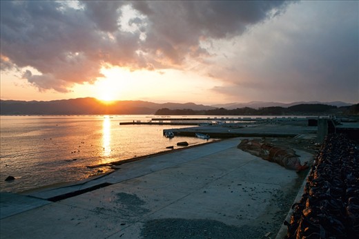 View over the damaged harbour facilities at Otomo fishing port. In the distance float newly constructed scallop fishing platforms.  Local fisheries have been slowly getting back into operation but often at a smaller scale than before.
