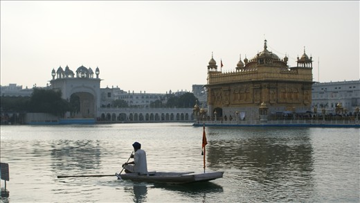 Golden temple in Amritsar and a man in a boat. 