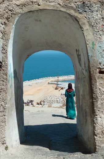 Passing by a gate, there stands the lady in blue, completing the view.