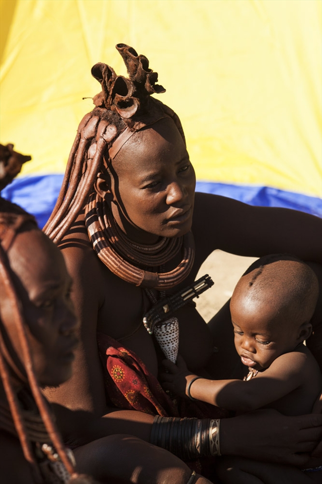 Women gather by the sacred fire to care for the kids. The Himbas use a mix of ochre and fat to avoid sunburn and skin infections. 