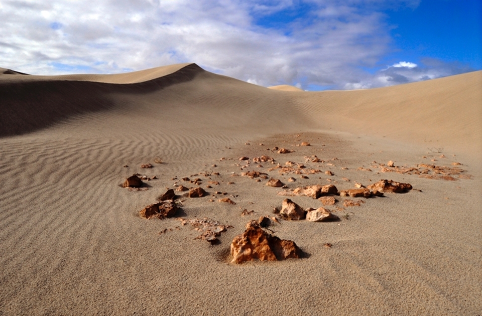 Here lies the remains of an early outback dwelling – broken rock littering the desert floor. This building, destroyed by the movement of the dunes, is successively hidden and revealed as a function of the wind. The image speaks to the human drama of survival in a challenging environment. 