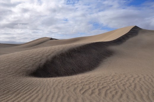 The beauty of these dunes belies their treacherous nature. Hills of sand stretch to the horizon, unspoilt by the presence of any living thing. The camera captures the symmetry and richness of the landscape, supporting a mirage of vitality amongst desolation.