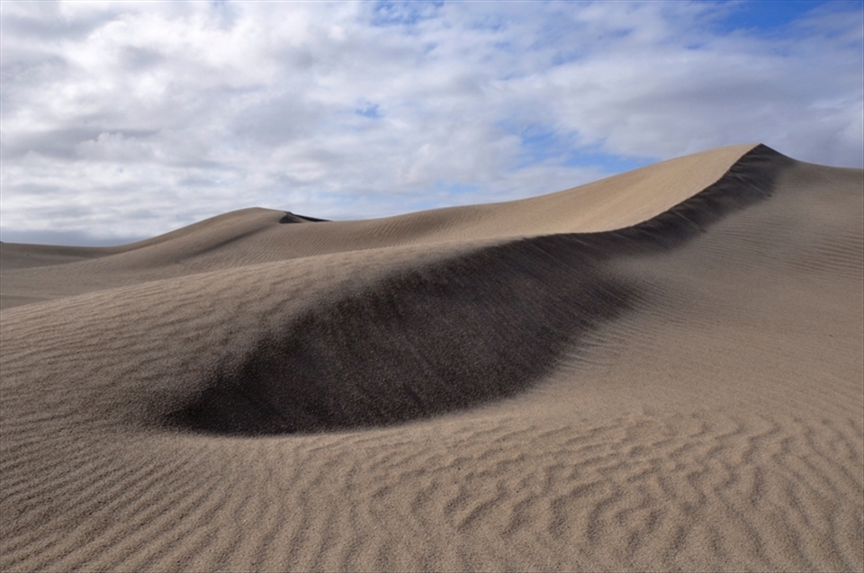 The beauty of these dunes belies their treacherous nature. Hills of sand stretch to the horizon, unspoilt by the presence of any living thing. The camera captures the symmetry and richness of the landscape, supporting a mirage of vitality amongst desolation.