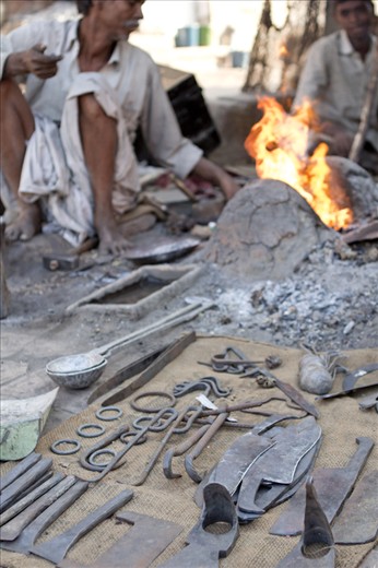 Many blacksmiths can be seen working in the streets of India. They simply insert a grate into a hole dug in the ground and a simple hand crank blower is then usually operated by his wife or a son.  
Unfortunately this job alone is not enough to support a whole family thus it is usual for them to have a second occupation.