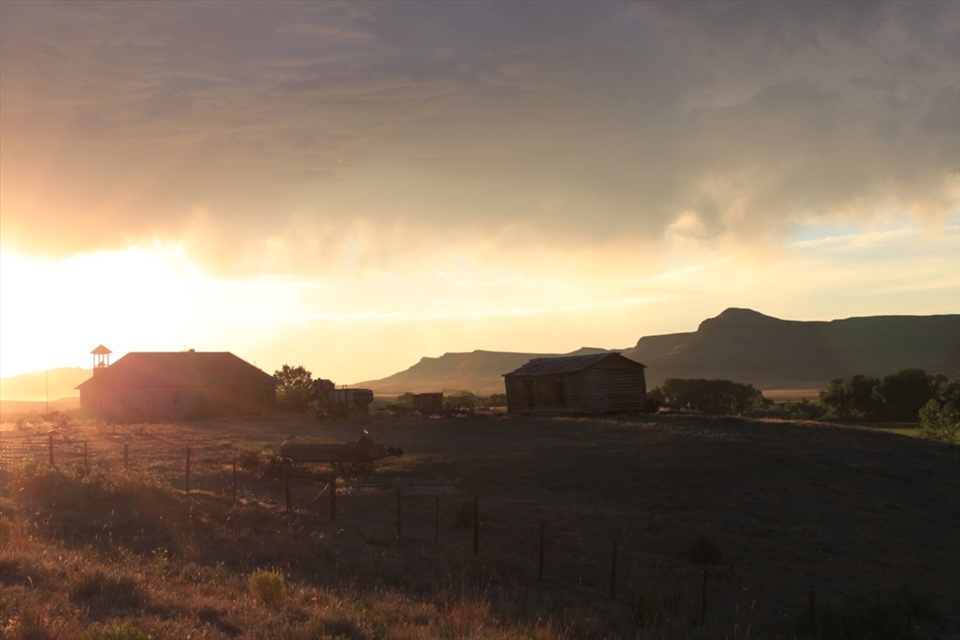 The sun sets after a seering hot day over an abandoned farm in Wyoming