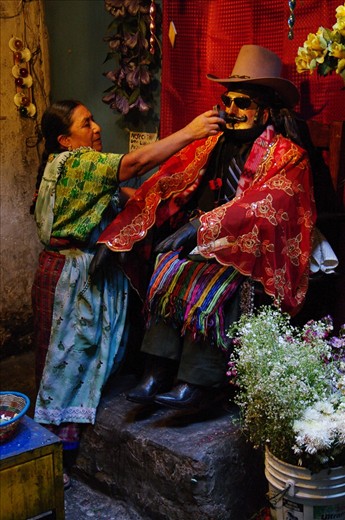 A wooden Maximon is offered a smoke from a wooden pipe as incentive to answer locals' prayers.