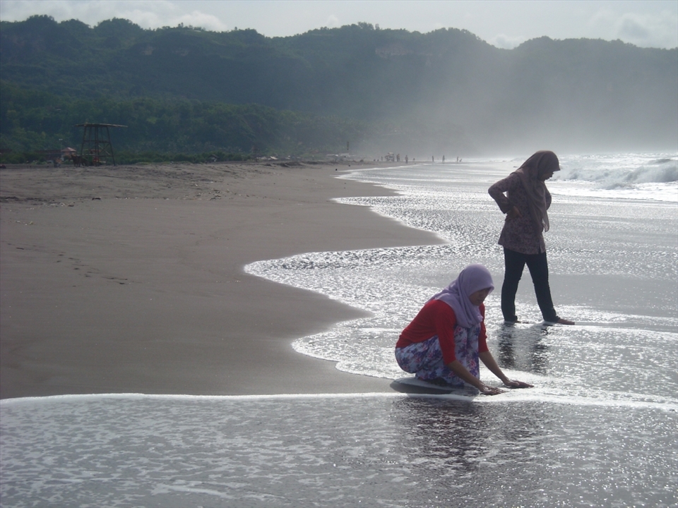 Sunny morning in Parangtritis beach, the waves were a little tight, but then fun. The sunlight which is highlights in one corner and the water who looks sparkling cause admiration for the two girls who enjoy the sea.