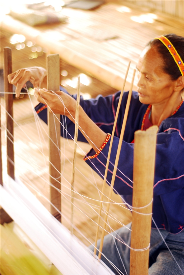 Baye Omeng sets the cotton fibers as the warp on the loom that has been passed down for generations. She relays that they consider this loom to be one of their prized possessions. 