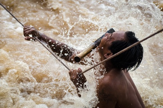 The fisherman holds on for his life knowing that one mistake here would result in certain death. The ranging Mekong pulls at his body as his weary arms cling desperately to hold him on the rope. Times like these rely on full concentration and both hands on the rope at a time, any extra luggage has to go in the mouth, knives included.