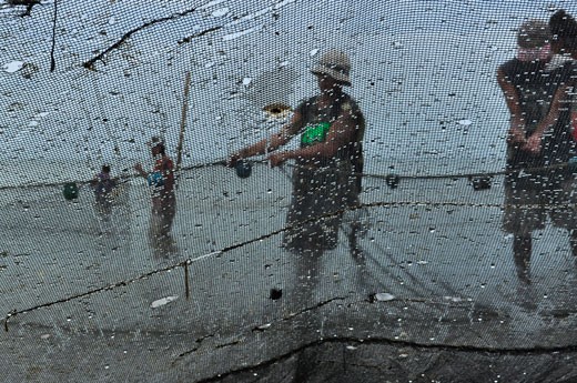 2.	The Fishermen’s Life. Fishing is one of the most popular sources of living among Filipinos who lives along the coastline. Every day, the fishermen wakes up before dawn and prepare their fishing gears. They ignore the cold temperature because they need to, they almost don’t have a choice. In taking the picture, I bent down so that the net filled the frame and the fishermen were put inside it. My primary objective was to take a picture that was compost not in a unique way. But, the picture exhibits a lot of symbolism. The net surrounds the fishermen which symbolizes that their lives depends so much on fishing. The holes and stitches in the net symbolizes that it endured a lot of work already. The picture symbolizes that in unity there is strength. That symbolism are exhibited through the net (threads that were bounded together) and the group of fishermen working together to get a bountiful catch. This picture was taken on a Saturday morning in Tigbauan in Iloilo.