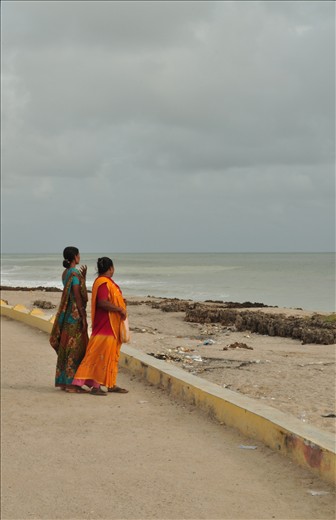 Two Indian women take in the beauty of the ocean while walking along the beach.