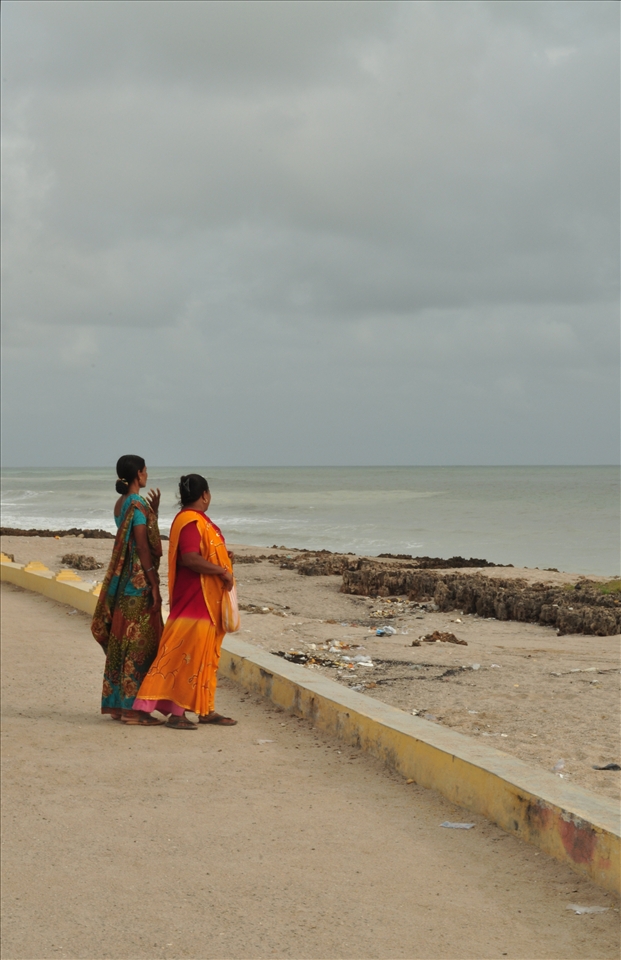 Two Indian women take in the beauty of the ocean while walking along the beach.