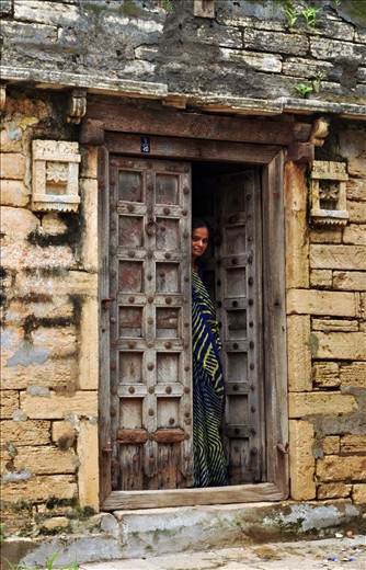A curious yet cautious woman peers through her doorway.