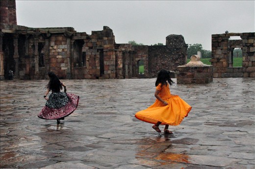 Two young girls play among ruins after a rainy morning.