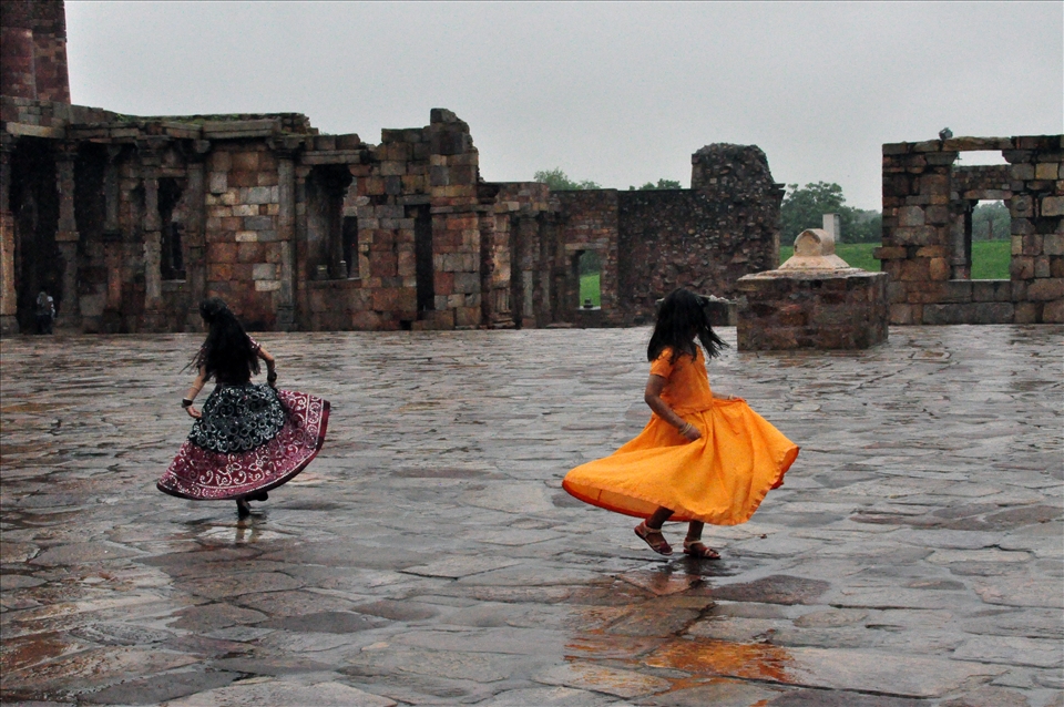 Two young girls play among ruins after a rainy morning.