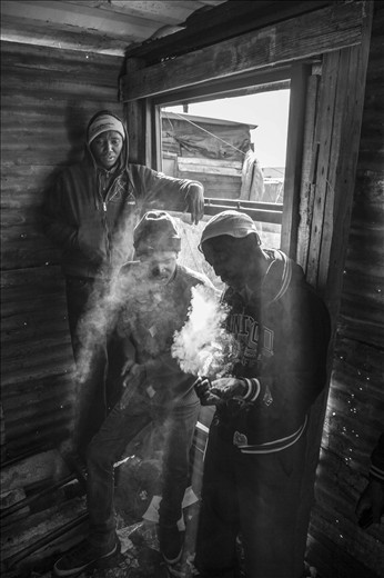 Waqa (far right) and two friends hang out at a local rapper’s house and pass the time smoking dakka out of a broken glass bottle top. While Spaza music is his passion, there are few opportunities to express it and many days end up just like this.