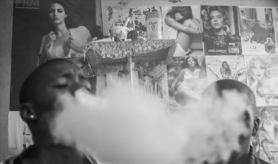 The Spaza lifestyle is modeled on an extravagant, western hip-hop culture, a grand but elusive dream for Waqa and his friends. Born with so little, their hope for a better life is grandiose. Under the gaze of beautiful, unattainable women, dakka smoke masks Waqa and a friend’s faces. In desperate pursuit of something bigger, these young men exist in a fog that obscures the path between their dreams and their reality.