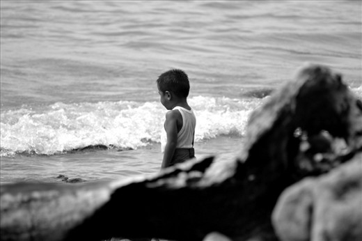 This little boy observes the waves as it slap on the shore. Building up courage for a dip by himself. 