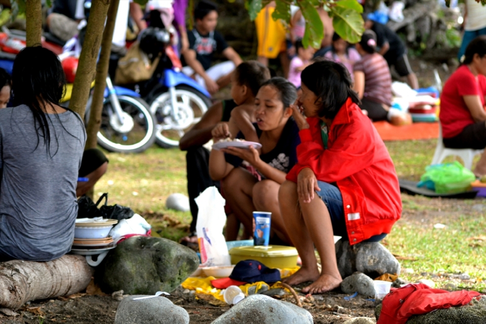 Zamboanga City, Philippines is surrounded with shorelines. Zamboangueños tend to celebrate most occassions on the beach. This is New Year's Day on Ebenezer Bible College Beach. Families gathered to reconnect with each other. On this photo, a family having their meal with only a rock or a log of wood to sit on.