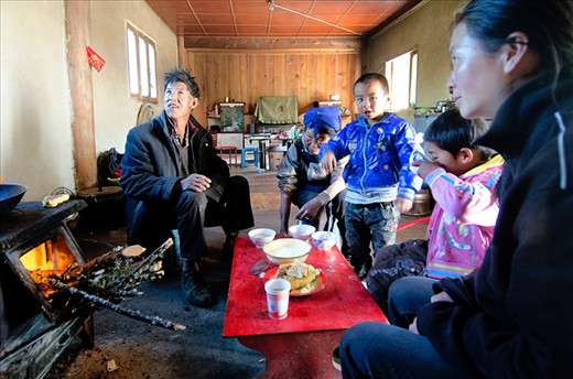 Family having lunch infront of the stove that is used to cook and keep warm.