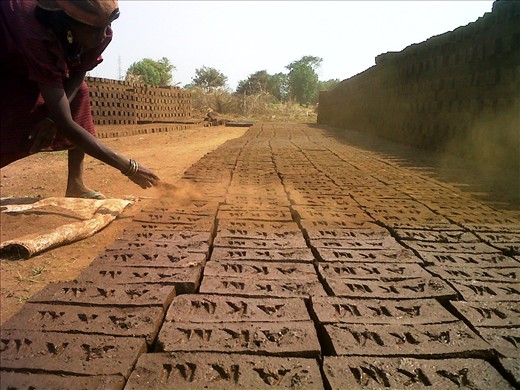 Fresh bricks being sprayed upon by brick powder by the woman before it dries up