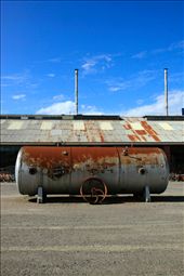 An unused tank just sitting smack in the middle of the junk yard in front of a warehouse storing various knick knacks.: by jas_pixel, Views[843]
