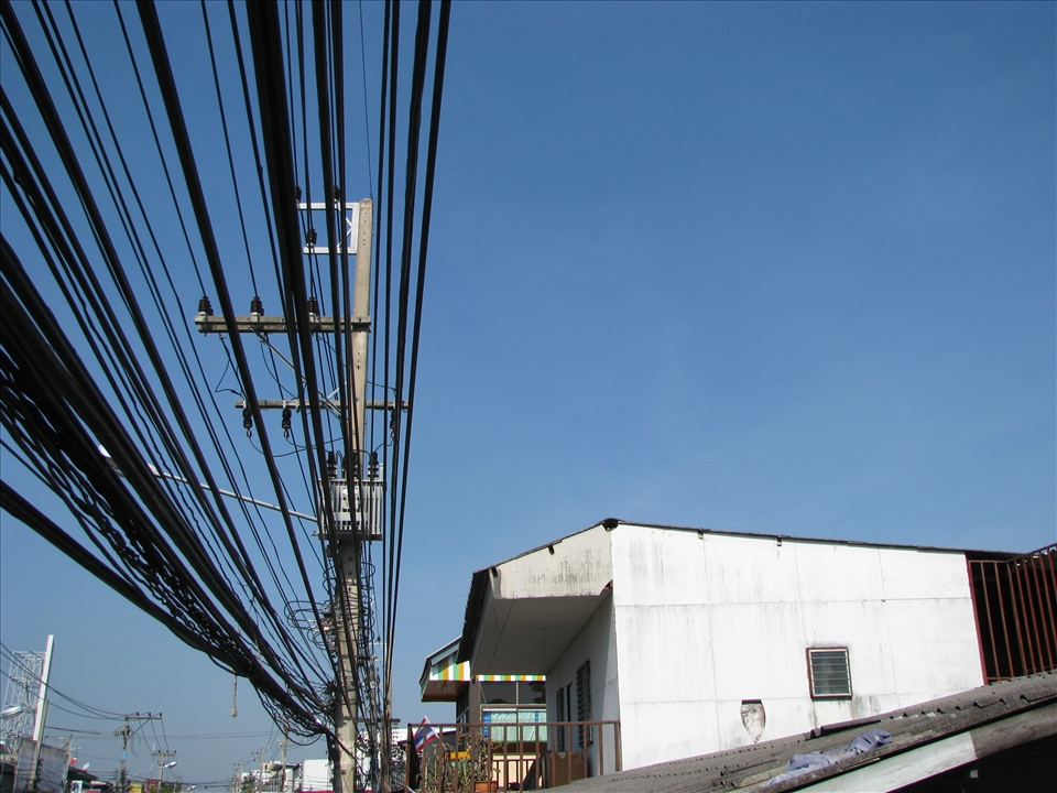 Modernity comes to Chiang Mai- cluster of power lines against a blue sky.