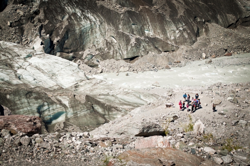 Fox Glacier is a 13 kms long glacier on the west cost of New Zealand's South Island. All groups visiting this glacier need to be briefed with health and safety instructions. This group prepares for their adventure on ice with a briefing from their leader. The surrounding ice slops reflect light to reveal a dark aqua colour through the mostly muddy surface.