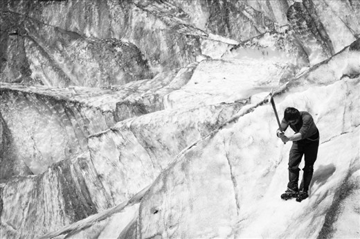 The group leader performs a balancing act and braves the steep slopes of the glacier to create footholds for the group to explore untouched parts of the glacier. 