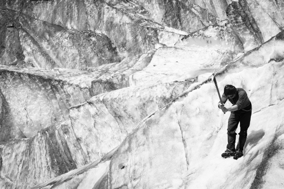 The group leader performs a balancing act and braves the steep slopes of the glacier to create footholds for the group to explore untouched parts of the glacier. 