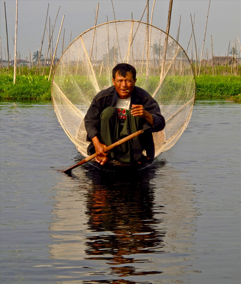 Inle fisherman checking nets while smoking cheroot 