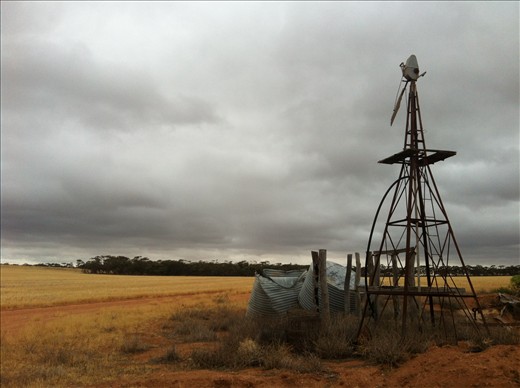 A Broken Windmill and Disused Tanks Stand in Isolation Under a Stormy Sky