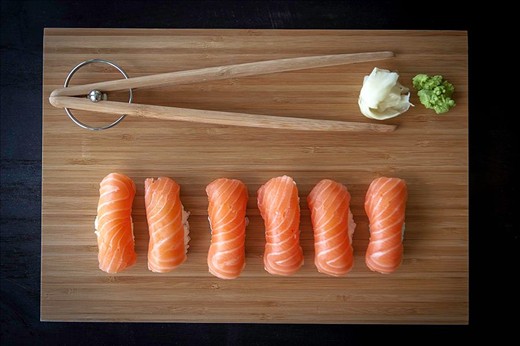 Bite-sized salmon ScandinAsian nigiri sushi in wood plank.