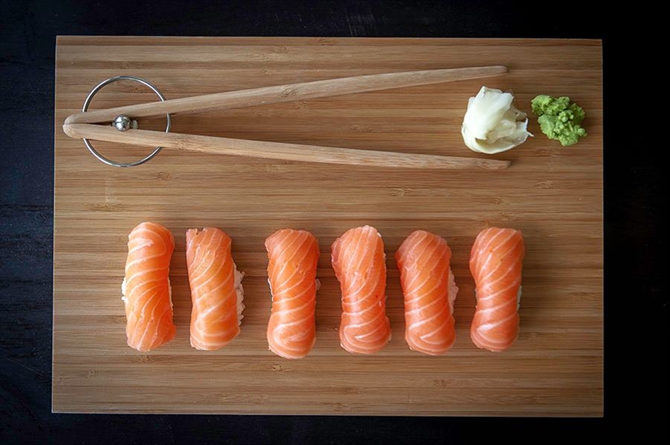 Bite-sized salmon ScandinAsian nigiri sushi in wood plank.